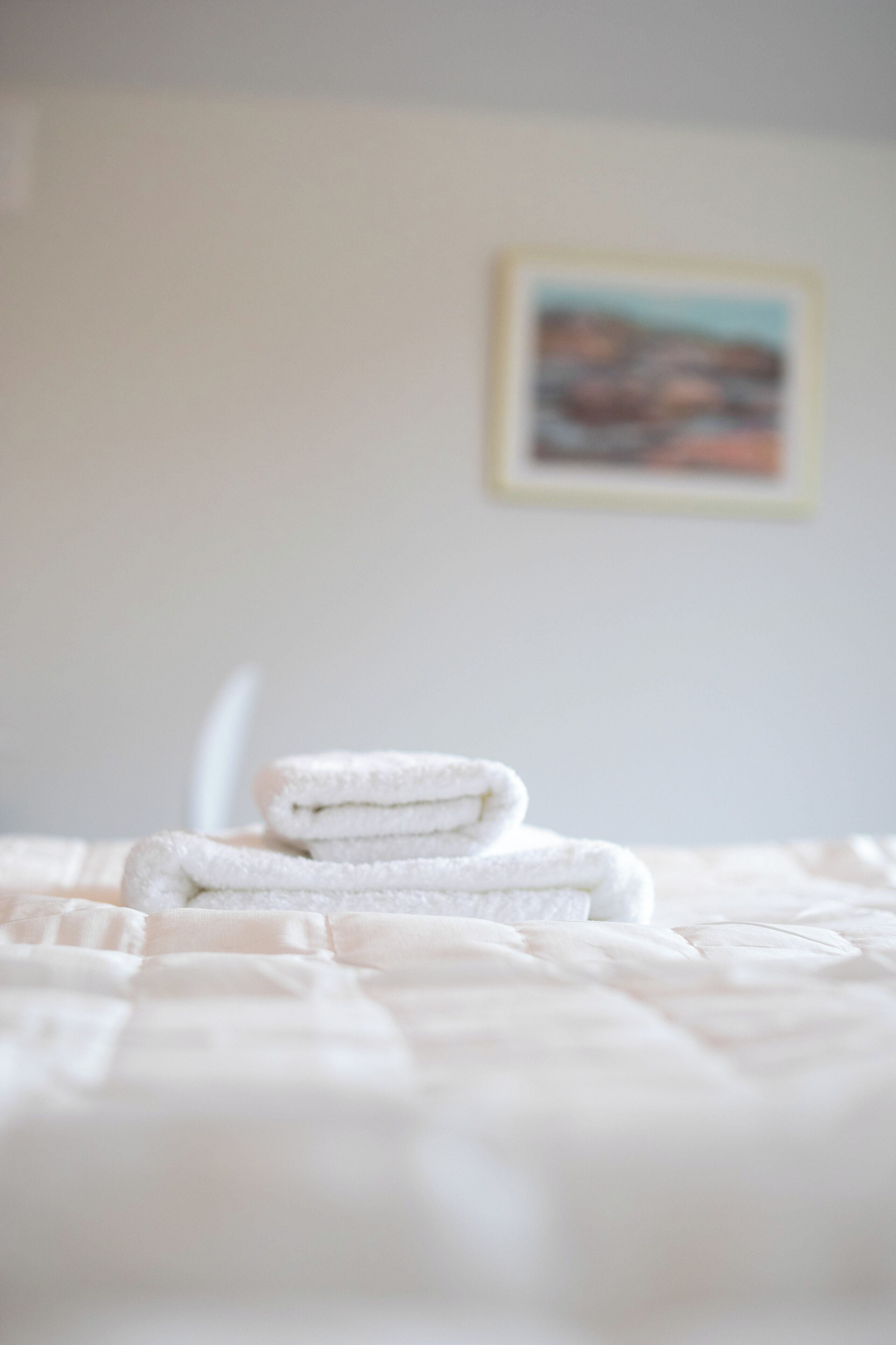 A neatly made bed with a folded white towel in the center.