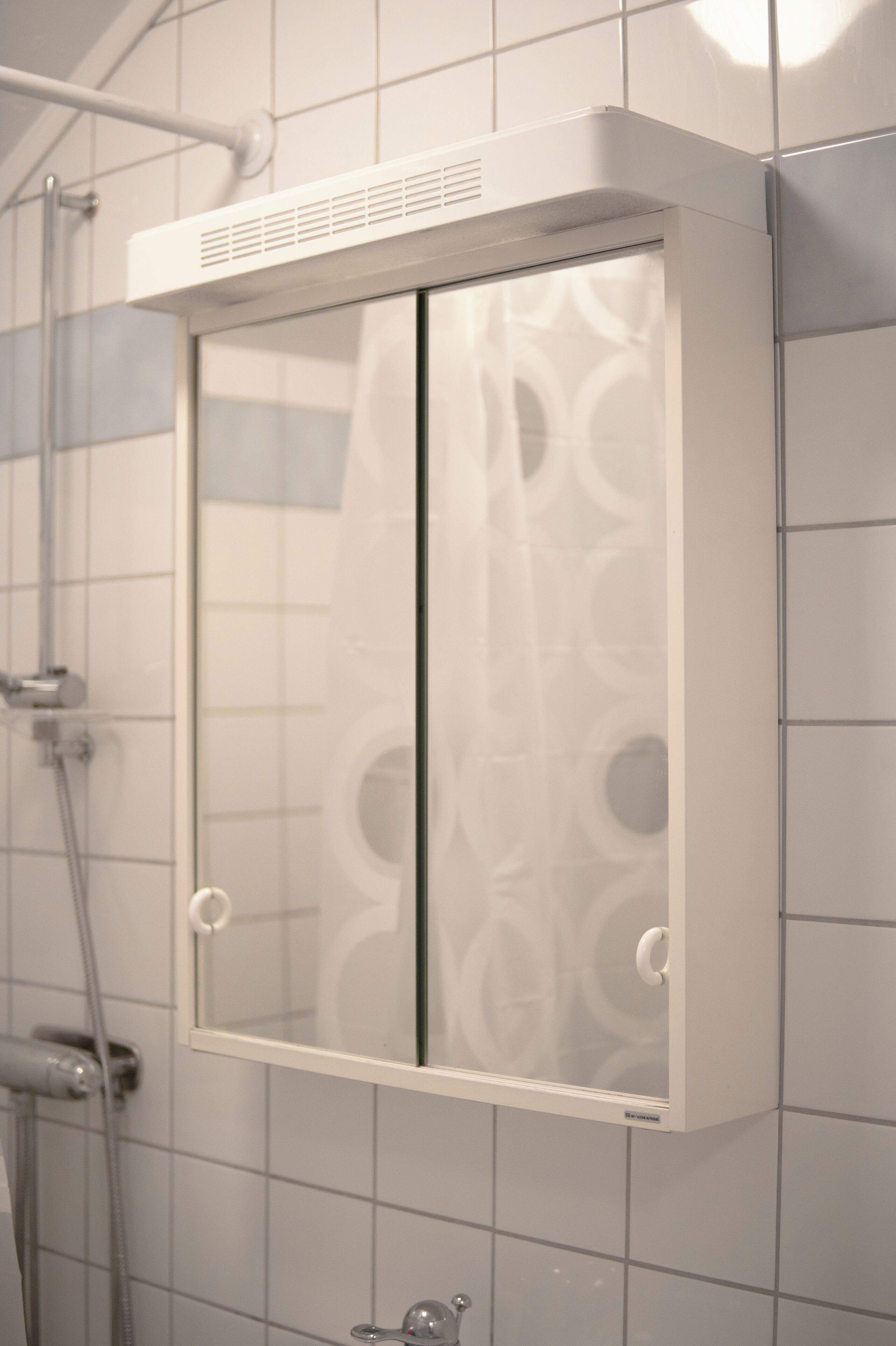 Une cabine de douche dotée d’une porte en verre et d’un système de ventilation situé au-dessus.