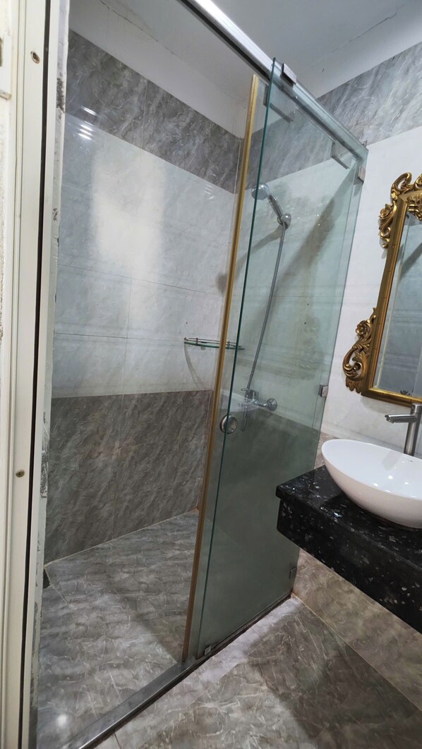 A bathroom with a glass-enclosed shower, marble flooring, and a gold-framed mirror. - Crowne Meow Bui Vien Hotel 2 (Ho Chi Minh City)