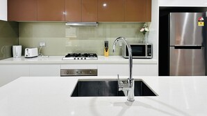 Una cocina moderna con electrodomésticos de acero inoxidable, horno empotrado, microondas y un lavamanos con un grifo elegante.