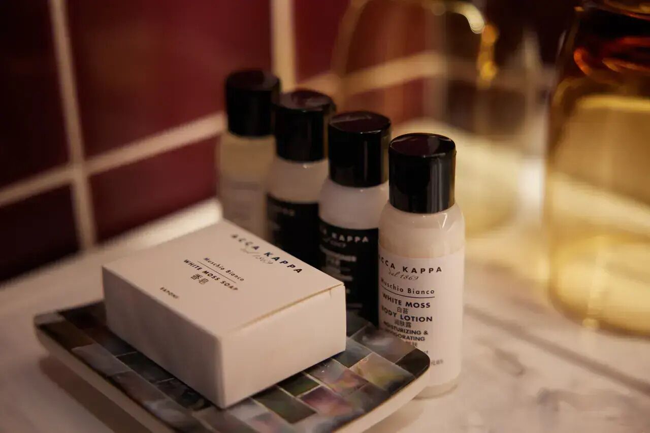 A bathroom with a white box labeled 'White Moss Body Lotion' and several bottles of the same product.