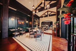 A restaurant with wooden beams, hanging lanterns, and a patterned rug.