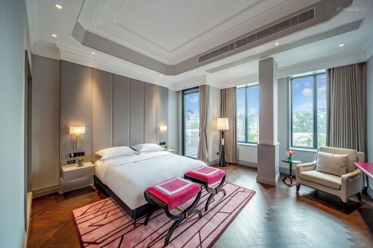A hotel room with a large bed, two bedside tables with lamps, a chair, and a view of the outdoors.