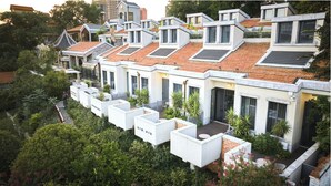 A modern residential building with multiple roof levels, a garden area with potted plants, and a pathway leading to the entrance. - Seclusion with the mountain (Wuhan)
