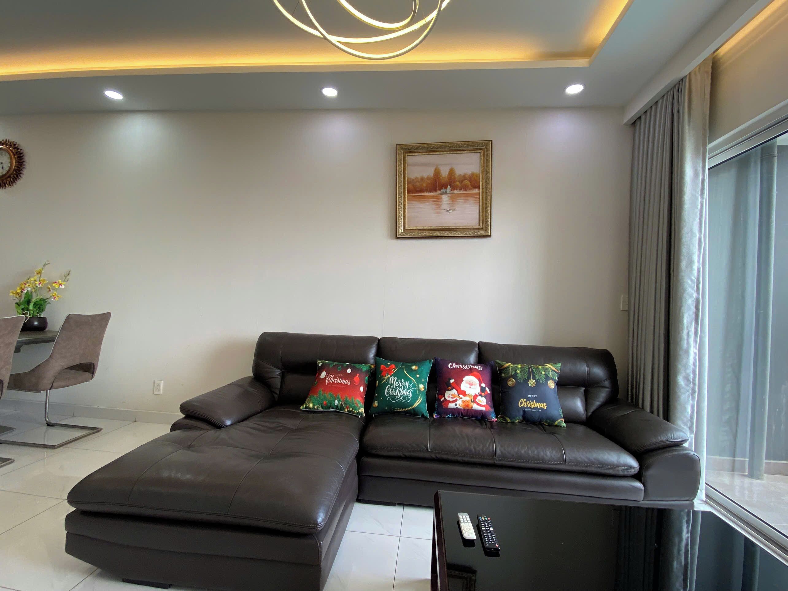 A modern living room with a sectional sofa, a coffee table with a remote control, and a framed picture on the wall.