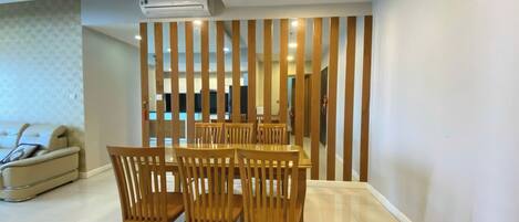 A modern dining area with a wooden table and chairs, a sofa, and a decorative wooden partition.