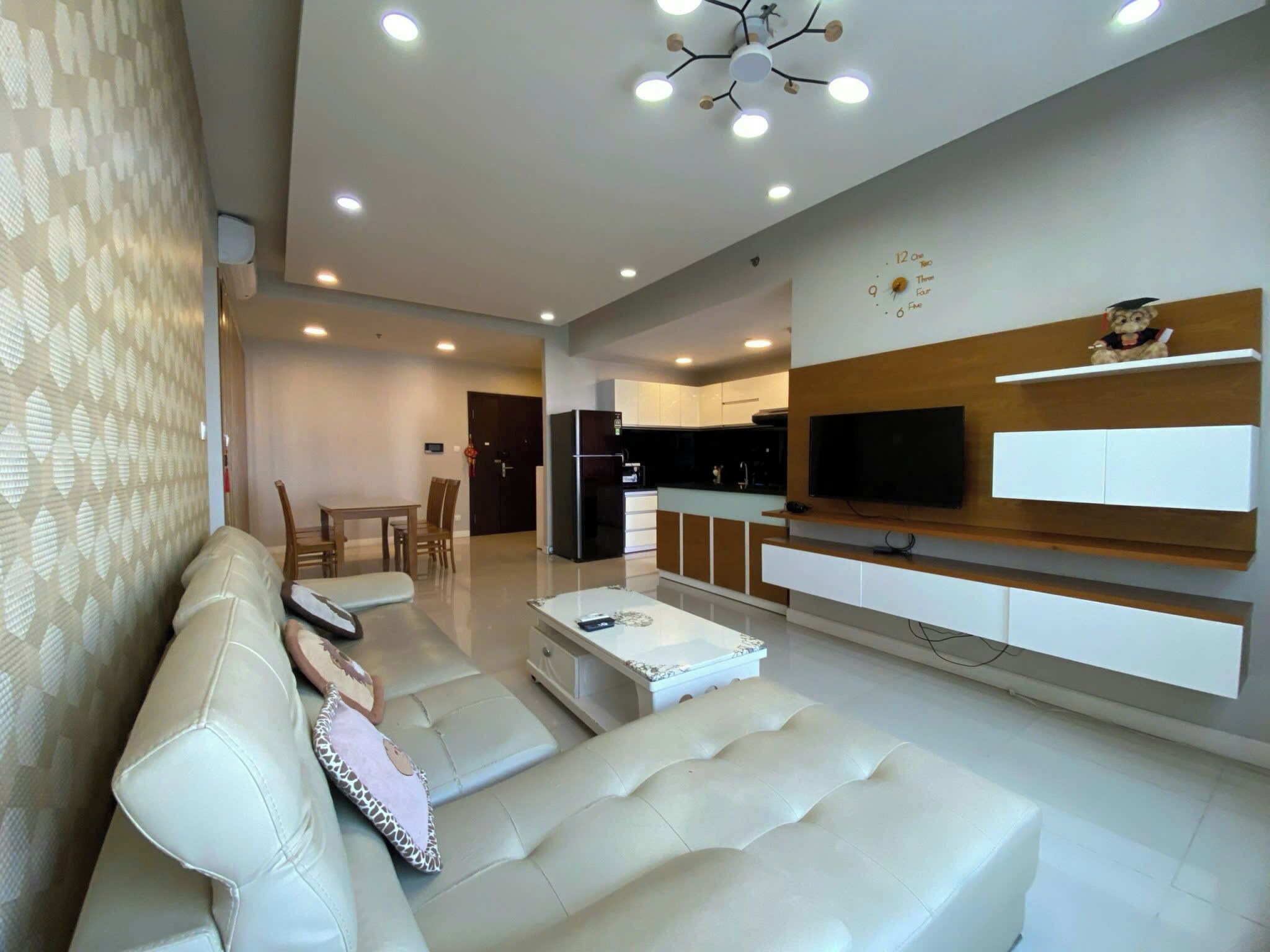 Una sala de estar moderna con un sofá, una mesa de centro y un televisor montado en la pared.