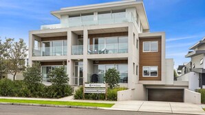 A modern multi-story residential building with a flat roof, large windows, and a balcony on the upper floor. - Walk to Beach and shops, Spacious, Ocean Views (Ocean Grove)