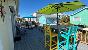 A wooden deck with outdoor furniture, including a table and chairs, and a green umbrella.