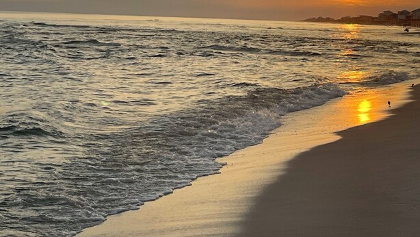 A beach at sunset with waves gently lapping the shore.
