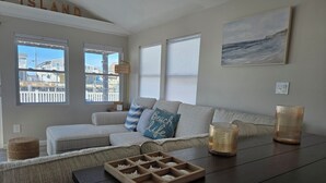 A living room with a sofa, cushions, a wooden tray, and a painting. - Beautifully updated waterfront home great for families & friends +beach badges. (Little Egg Harbor Township)
