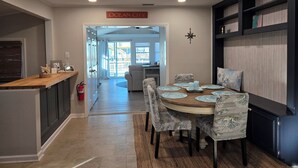 A modern kitchen with a wooden countertop, a dining area with a round table and patterned chairs, and a view of the backyard through a sliding glass door. - Beautifully updated waterfront home great for families & friends +beach badges. (Little Egg Harbor Township)