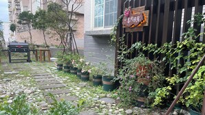 Un chemin de jardin bordé de plantes en pot et délimité par une clôture en bois.