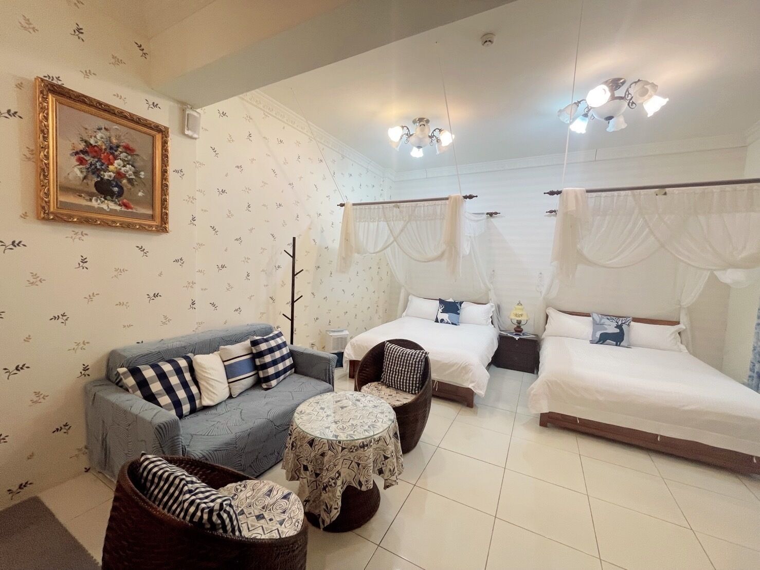 A room with a sofa, two beds, a small table, and a decorative painting.