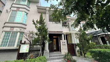 A traditional building with a symmetrical facade, large windows, and a central entrance with steps.