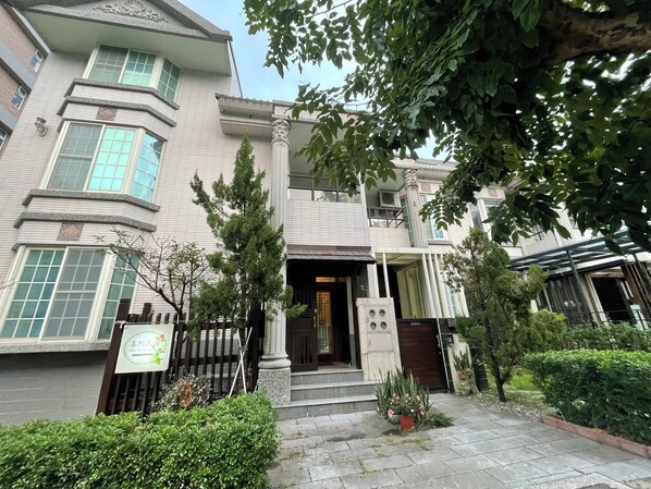 A traditional building with a symmetrical facade, large windows, and a central entrance with steps.