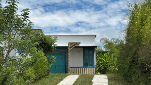 Un camino que lleva a una casa con puerta azul y paredes blancas.