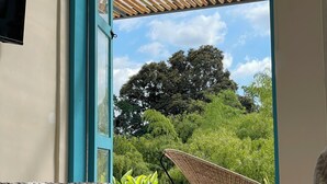 Un dormitorio con cama, ventana con techo de bambú y vistas al exterior.