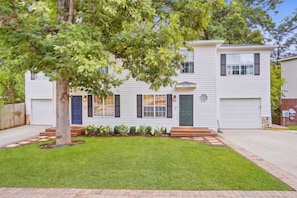 A two-story house with a front porch, a mailbox, and a well-maintained lawn.