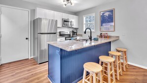 Una cocina moderna con una isla azul, electrodomésticos de acero inoxidable y taburetes de bar de madera.