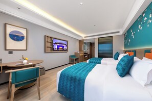Habitación de hotel con dos camas, un escritorio, una silla y un televisor.