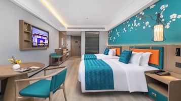 A modern hotel room with a large bed, a desk, a chair, a TV mounted on the wall, and a decorative wall mural.