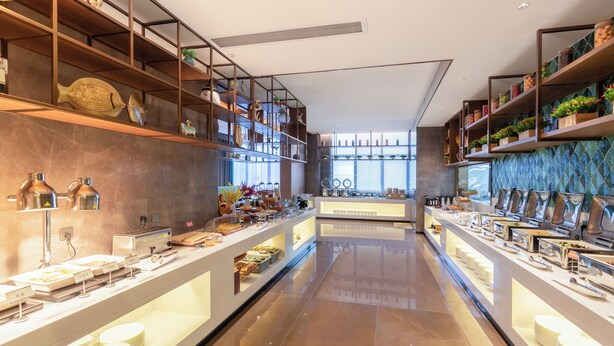 Un espace buffet moderne doté de plusieurs points de service, d’étagères ornées d’objets décoratifs et d’un sol propre et ciré.