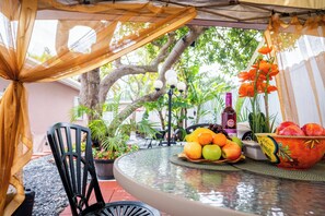 A round glass table with a fruit bowl, a bottle, and a potted plant. - Hidden Gem in Cutler Bay-Cozy 1BR Retreat Near It All w/Fast Wi-Fi & Parking! (Cutler Bay)