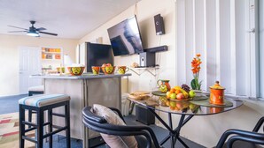 A modern kitchen with a built-in TV, a dining area with a glass table, and a bar counter with stools.
