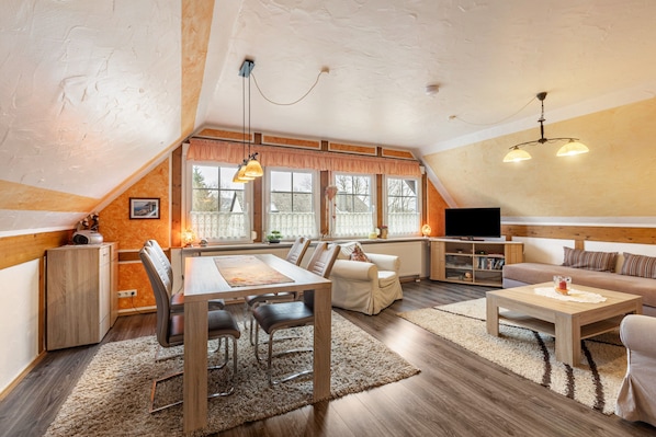 A cozy living room with a dining area, a sofa, a TV, and a fireplace.