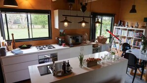 Una cocina moderna con una isla central, electrodomésticos integrados y una estantería llena de libros.