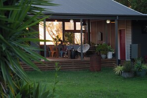 Ein Haus mit Veranda, Gartenmöbeln und Blumentöpfen.