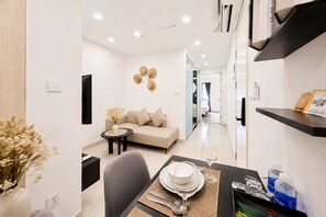 A modern hotel room with a sofa, dining table set, and a TV. - Sun Residences Hotel and Apartment (Hanoi)