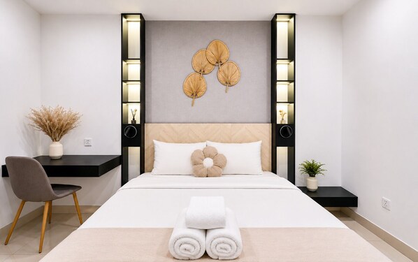 A modern hotel room with a bed, a desk, a chair, and a wall-mounted decorative piece.