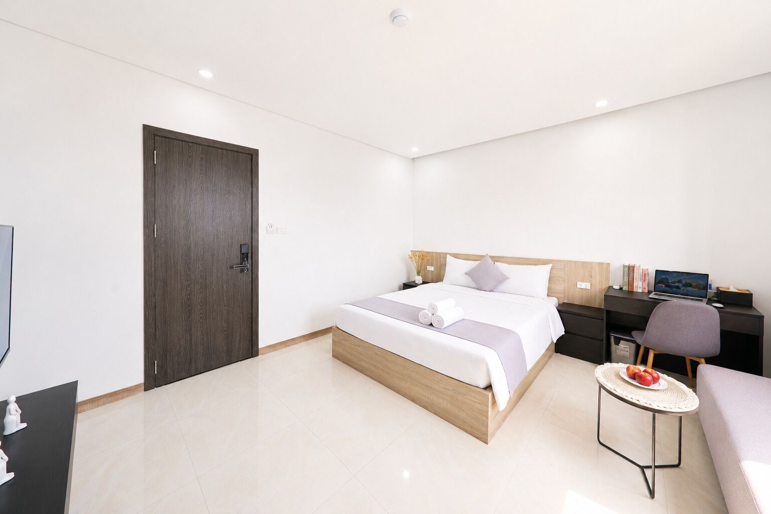 Una habitación de hotel moderna con cama, escritorio, silla y una pequeña mesa redonda.