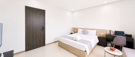 Una habitación de hotel moderna con cama, escritorio, silla y una pequeña mesa redonda.