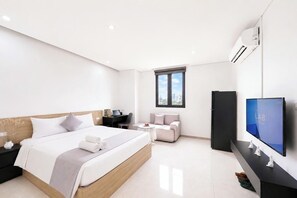 Une chambre d’hôtel moderne équipée d’un lit, d’un bureau, d’un canapé, d’une télévision et d’un appareil de climatisation.