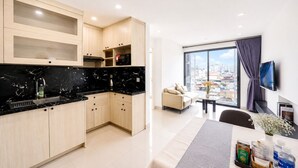 Una cocina moderna con encimera de mármol negro, armarios de madera y vistas a la ciudad a través de amplios ventanales.