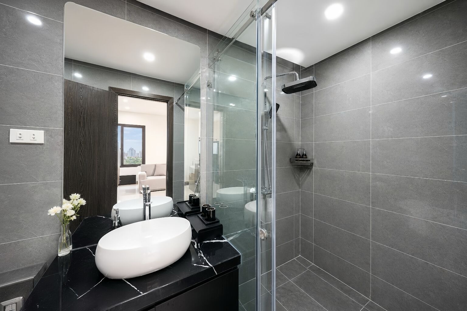 A modern bathroom with a glass-enclosed shower, a white sink, and a dark countertop.