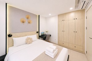 A hotel room with a bed, bedside table, desk, and wardrobe.