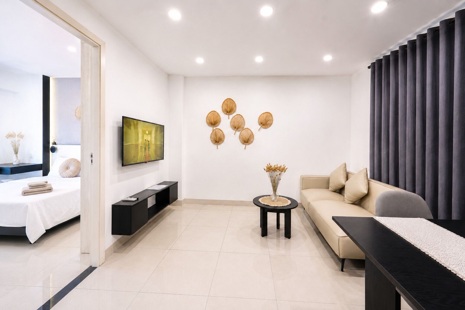 Un salon moderne avec un canapé, un téléviseur et des œuvres d’art décoratives au mur.