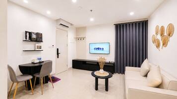 A modern living room with a sofa, a dining table with chairs, a TV, and a decorative wall piece.
