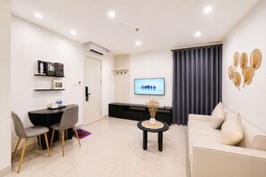 A modern living room with a sofa, a dining table with chairs, a TV, and a decorative wall piece.