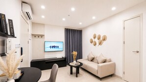 Una sala de estar moderna con sofá, una mesa de comedor con sillas, un televisor y decoración en la pared.
