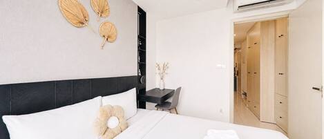 Una habitación de hotel moderna con cama, mesita de noche y escritorio con silla.