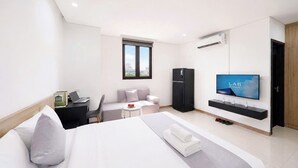 Habitación de hotel moderna con cama, escritorio, silla, televisor, armario y ventana.