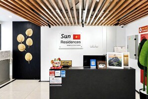 Una reception con una insegna per Sun Residences, un'area accoglienza e un pannello decorativo con motivi a foglia.