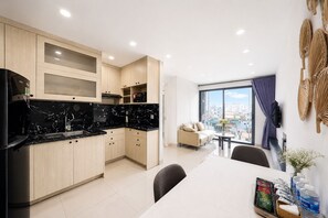 A modern kitchen with a dining area, a sofa, and a large window with a city view. - Sun Residences Hotel and Apartment (Hanoi)