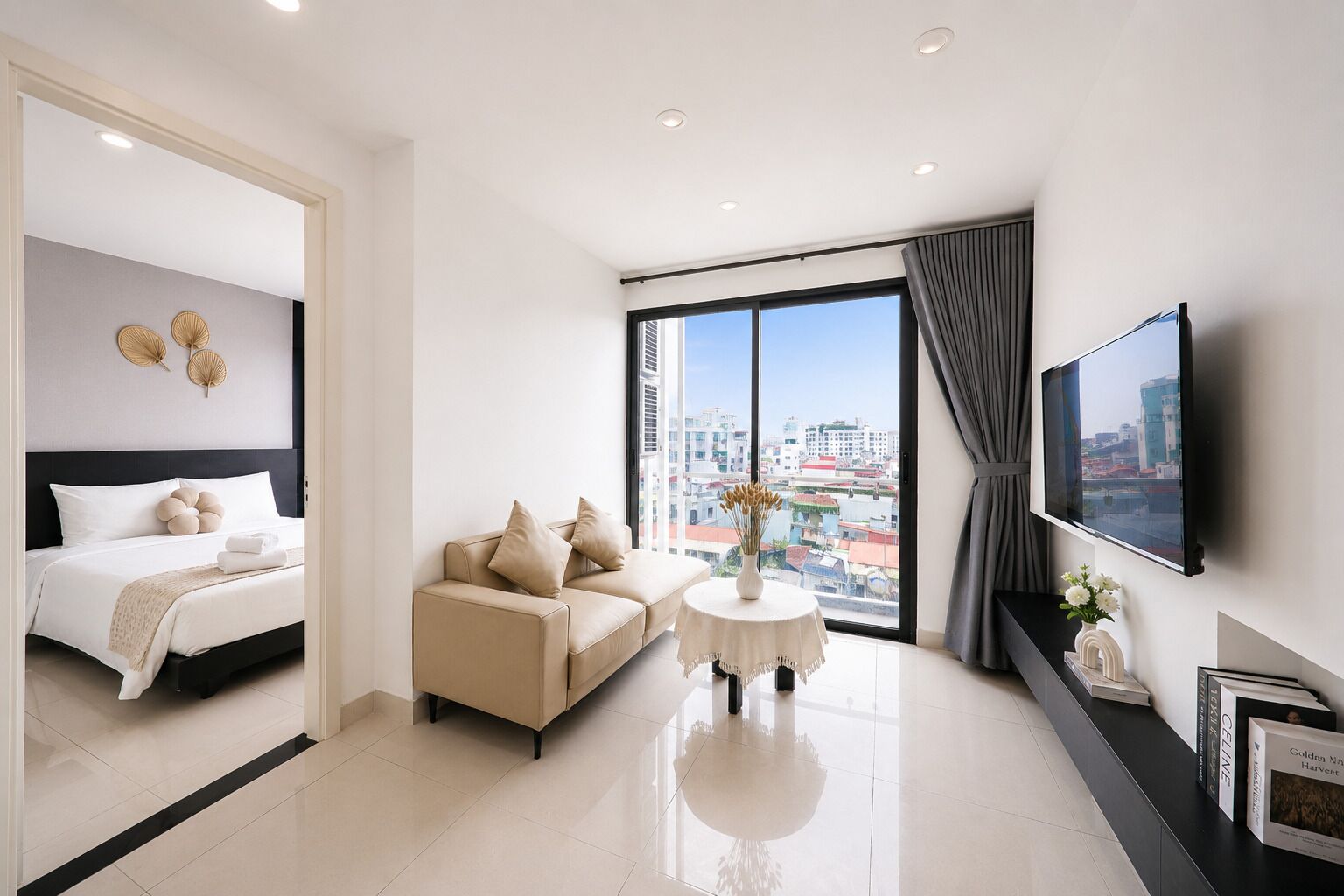 Quarto de hotel moderno com cama, um sofá, uma mesa pequena e televisão.