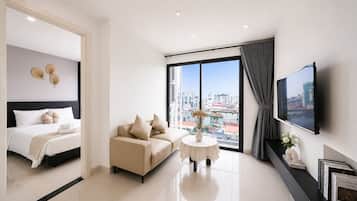 Quarto de hotel moderno com cama, um sofá, uma mesa pequena e televisão.